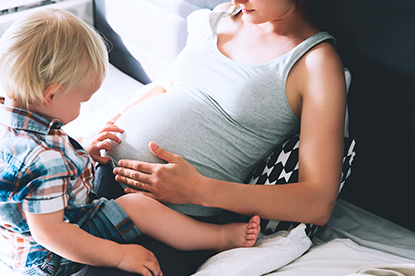 Zwangere vrouw met baby op schoot